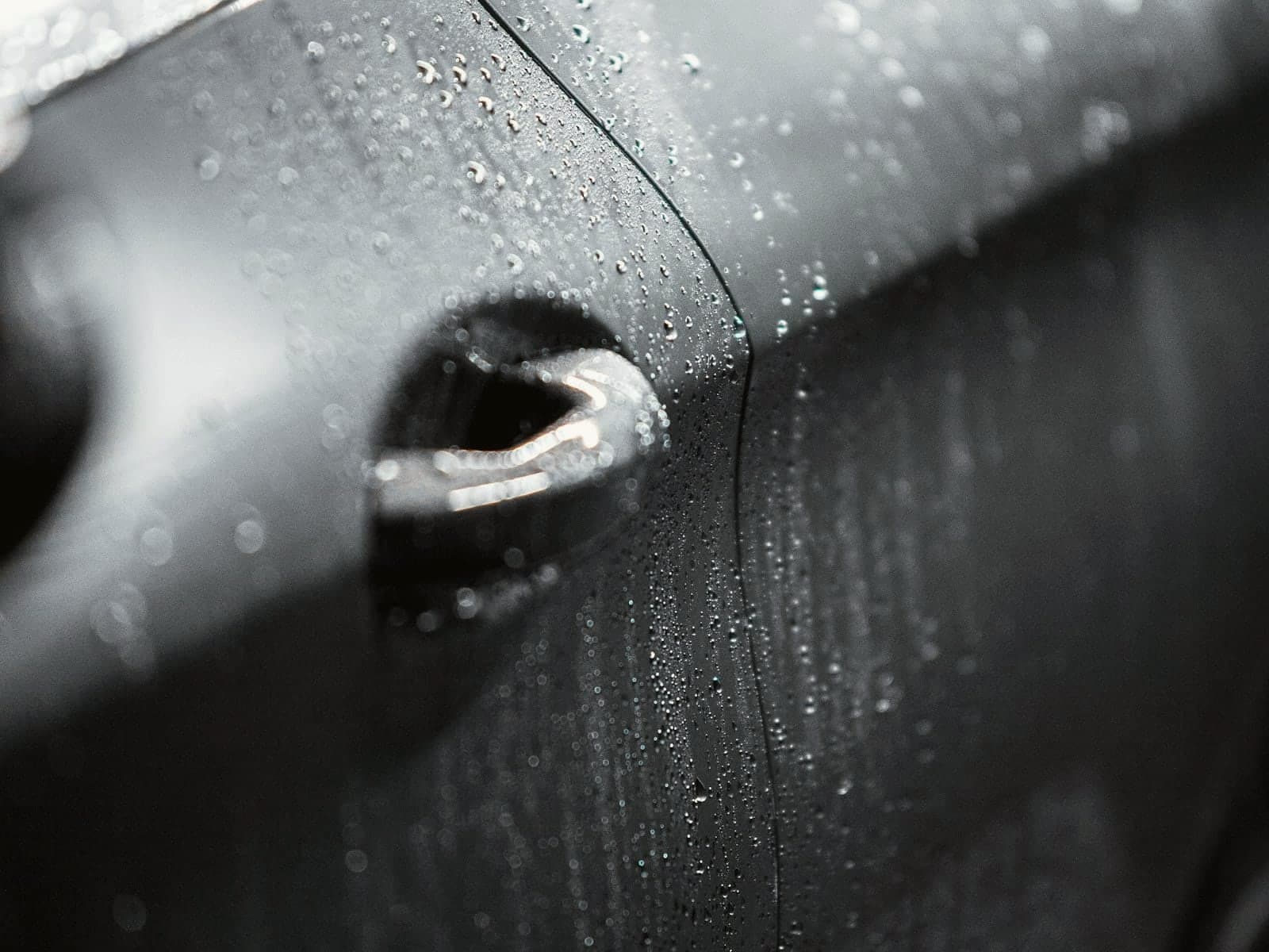 Water beading across a dark car door after a wash and seal